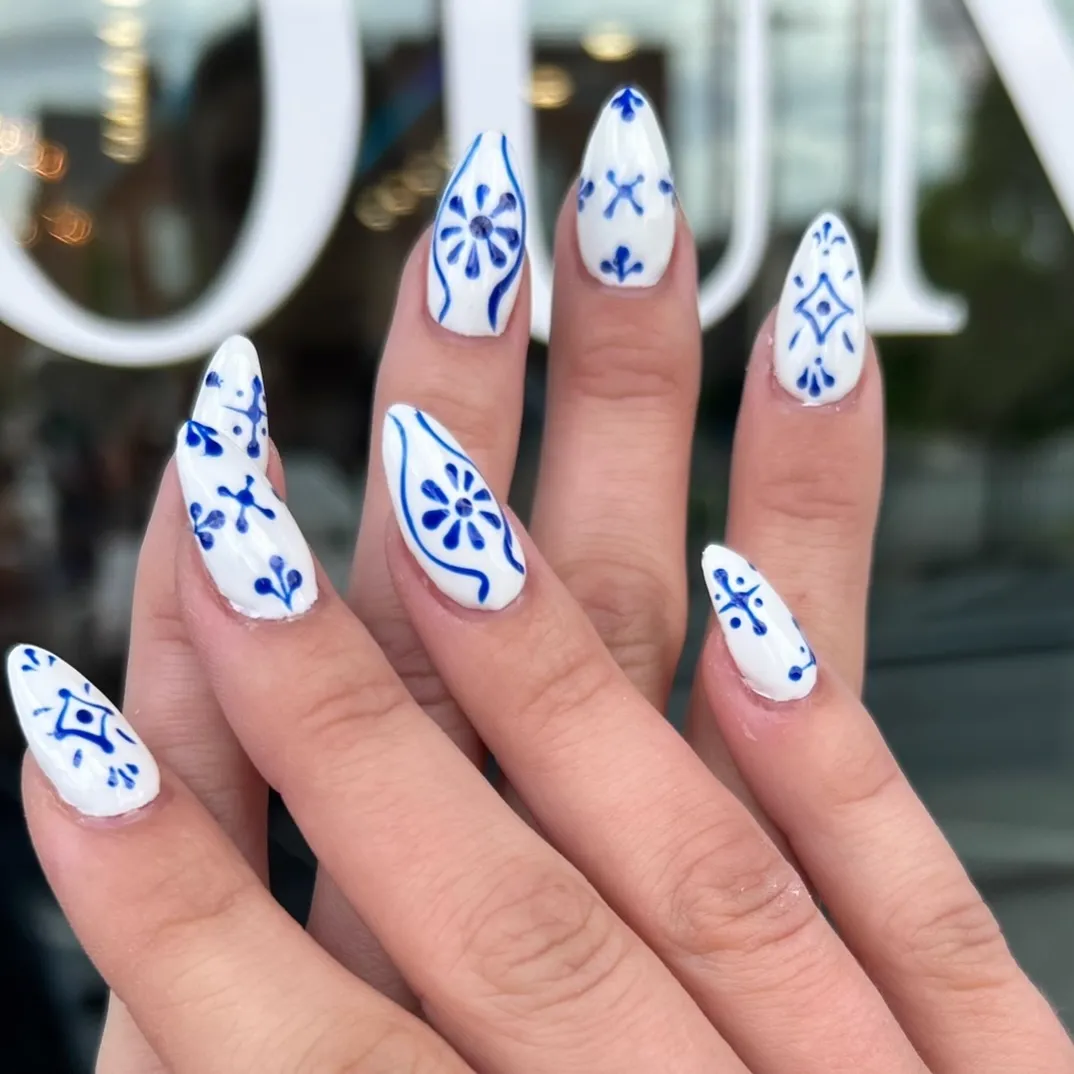White almond nails with hand-painted blue porcelain-style motifs