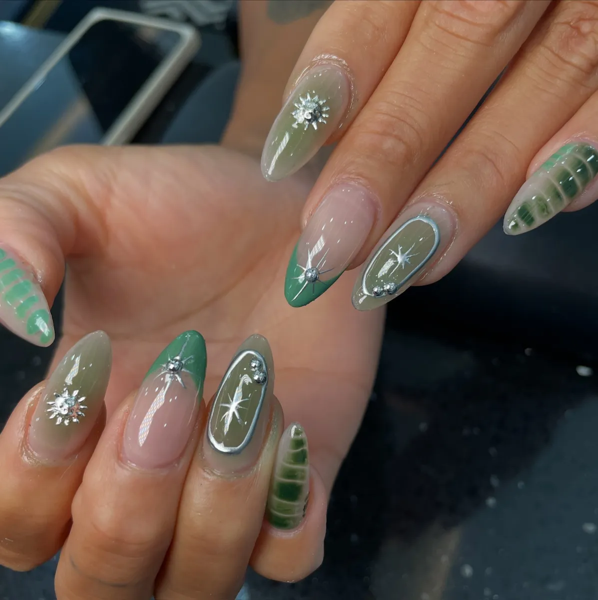 Almond nails in sage green with silver star charms and jelly accents