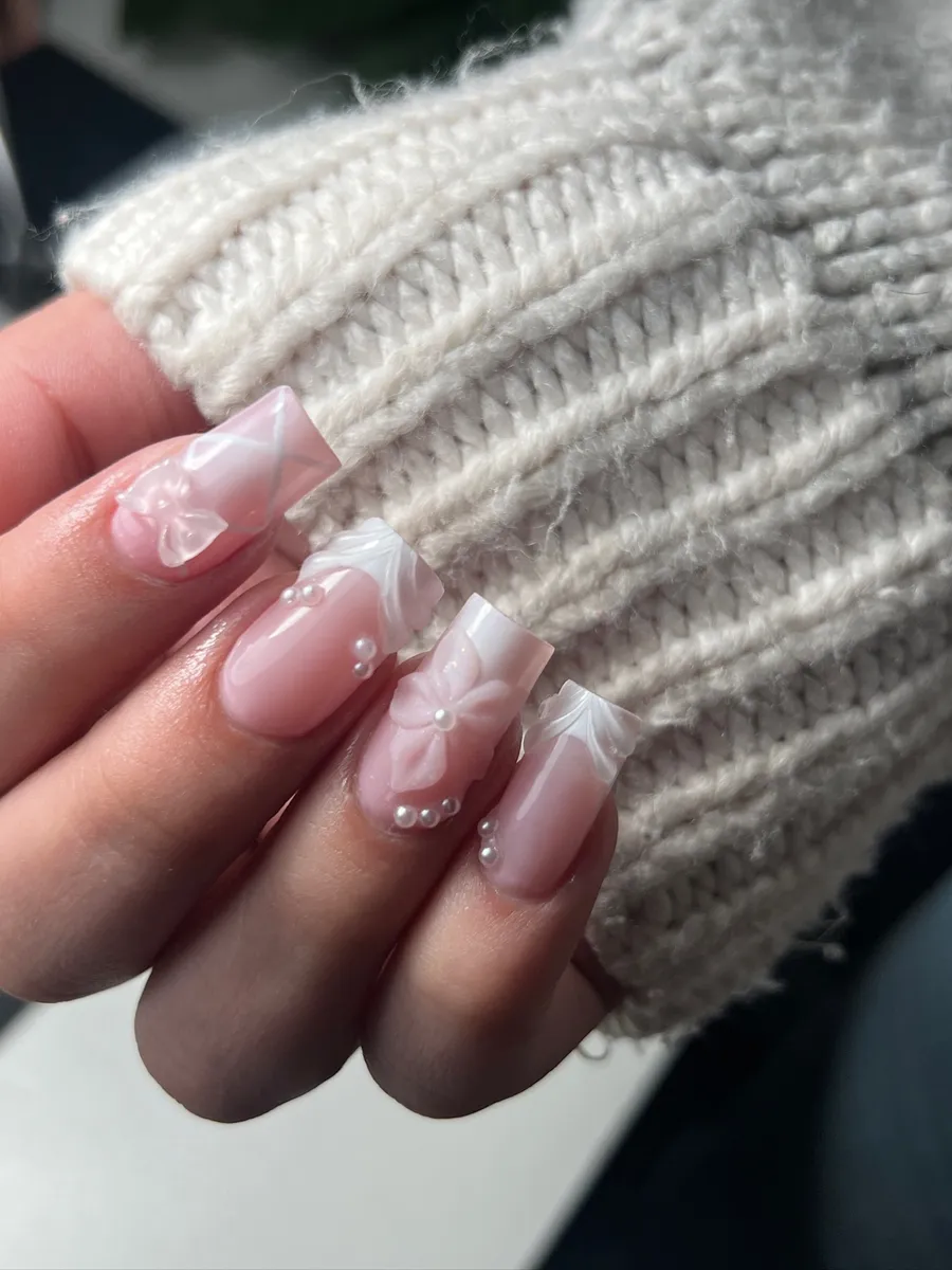 Short square nails with sheer pink base and white 3D bow and pearl accents