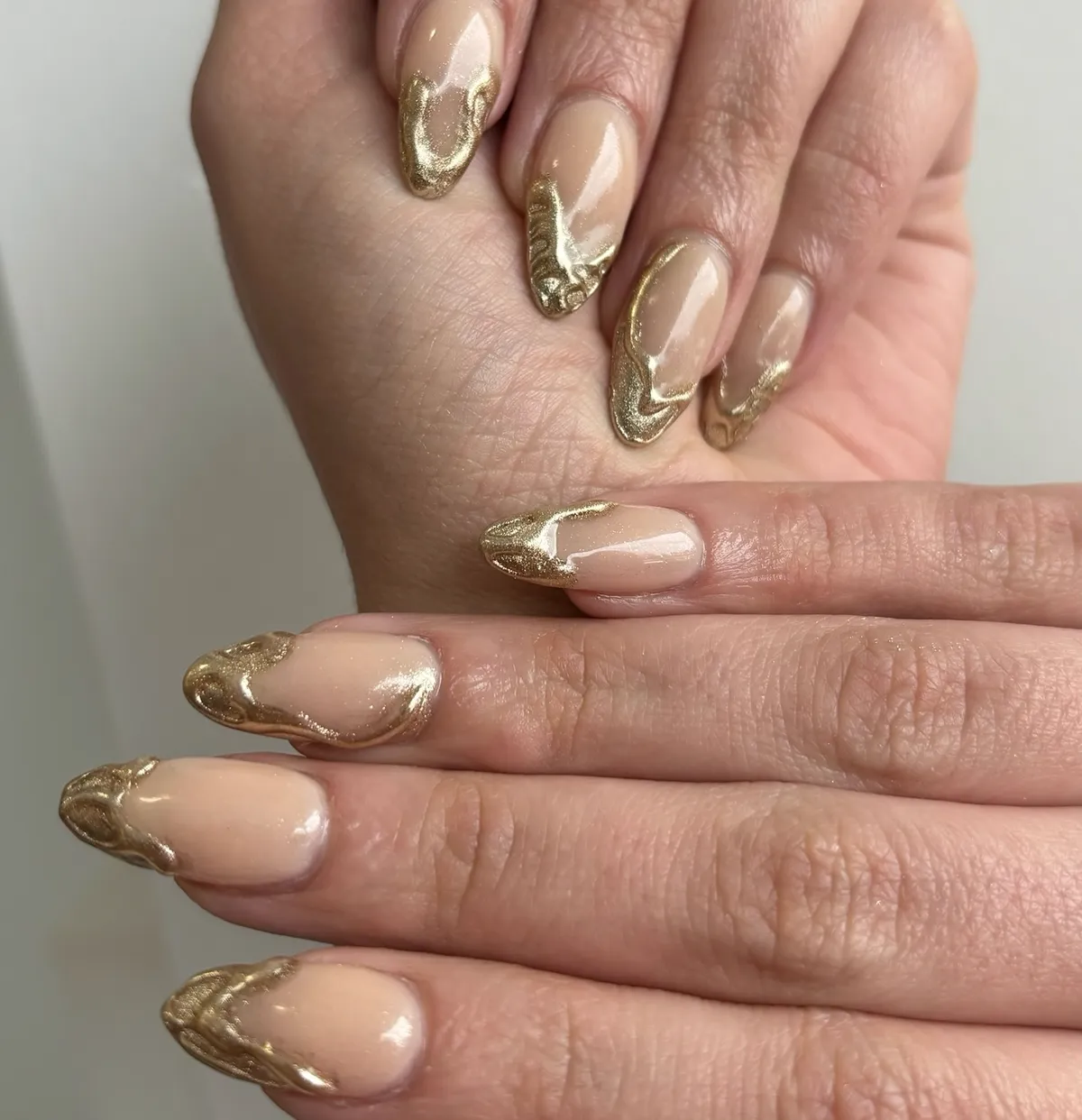 Nude almond nails with gold chrome swirl detailing
