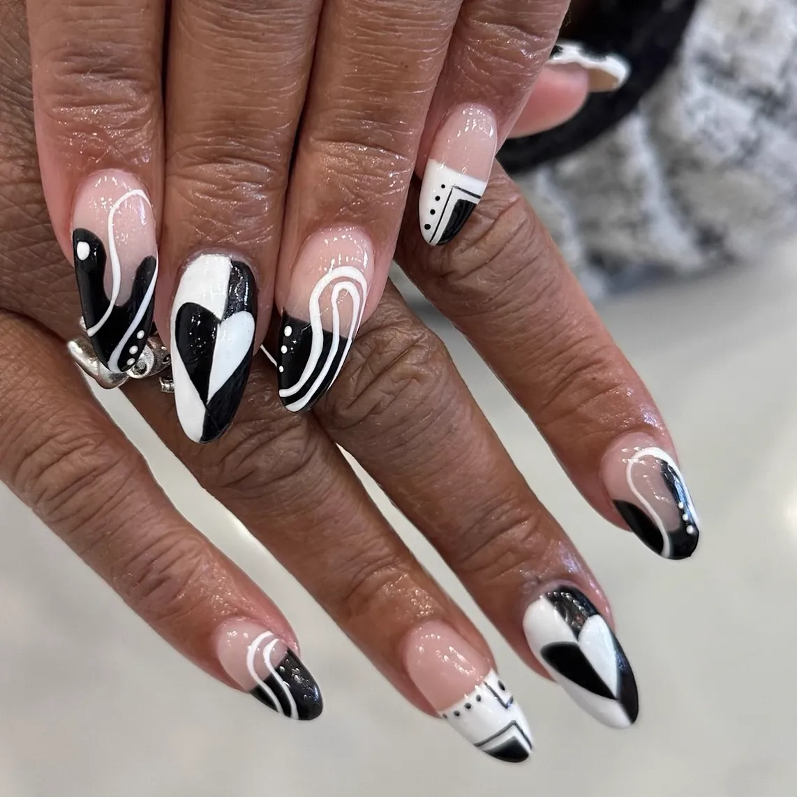 Black and white graphic nail art with hearts and fine line work