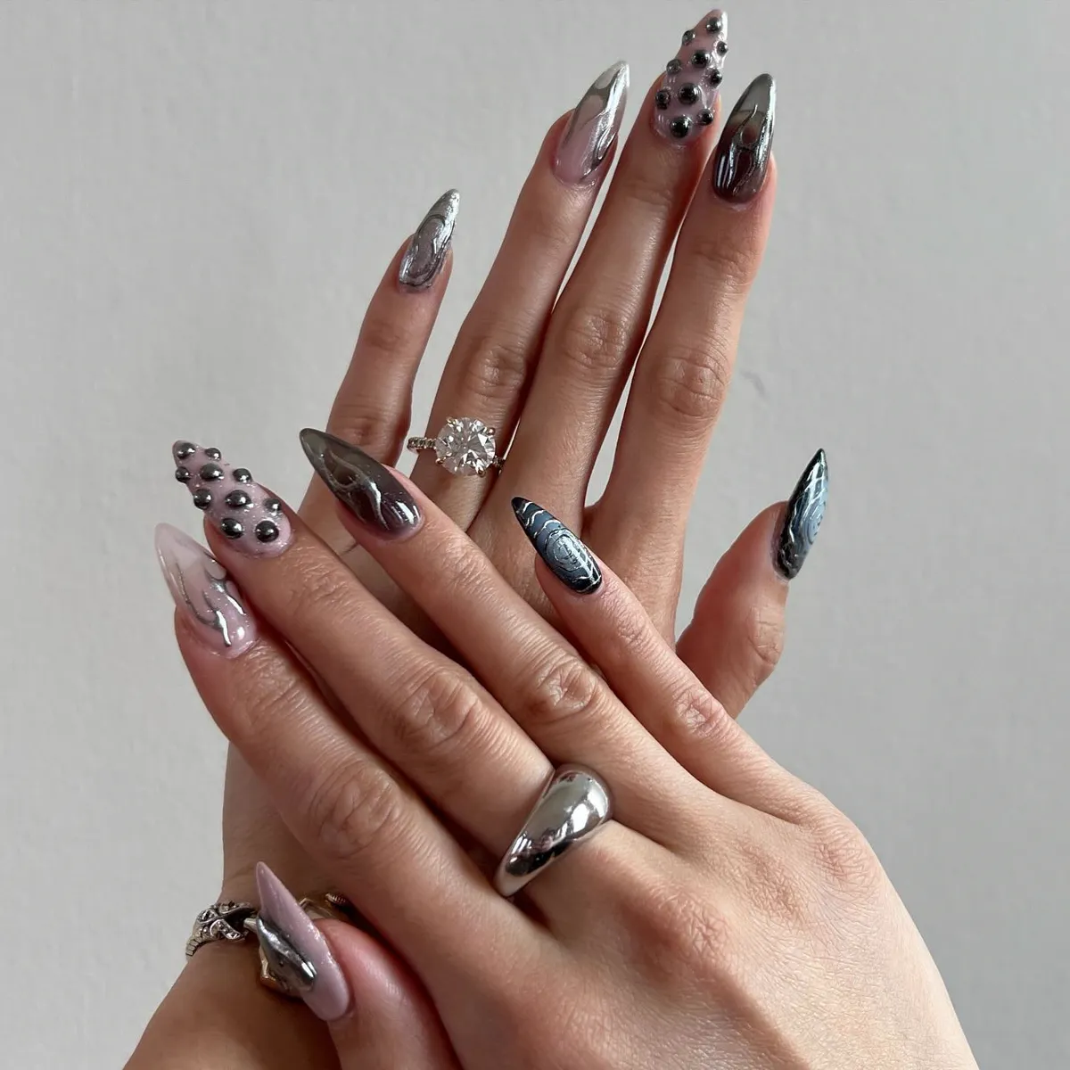 Silver chrome stiletto nails with rhinestone and charm accents